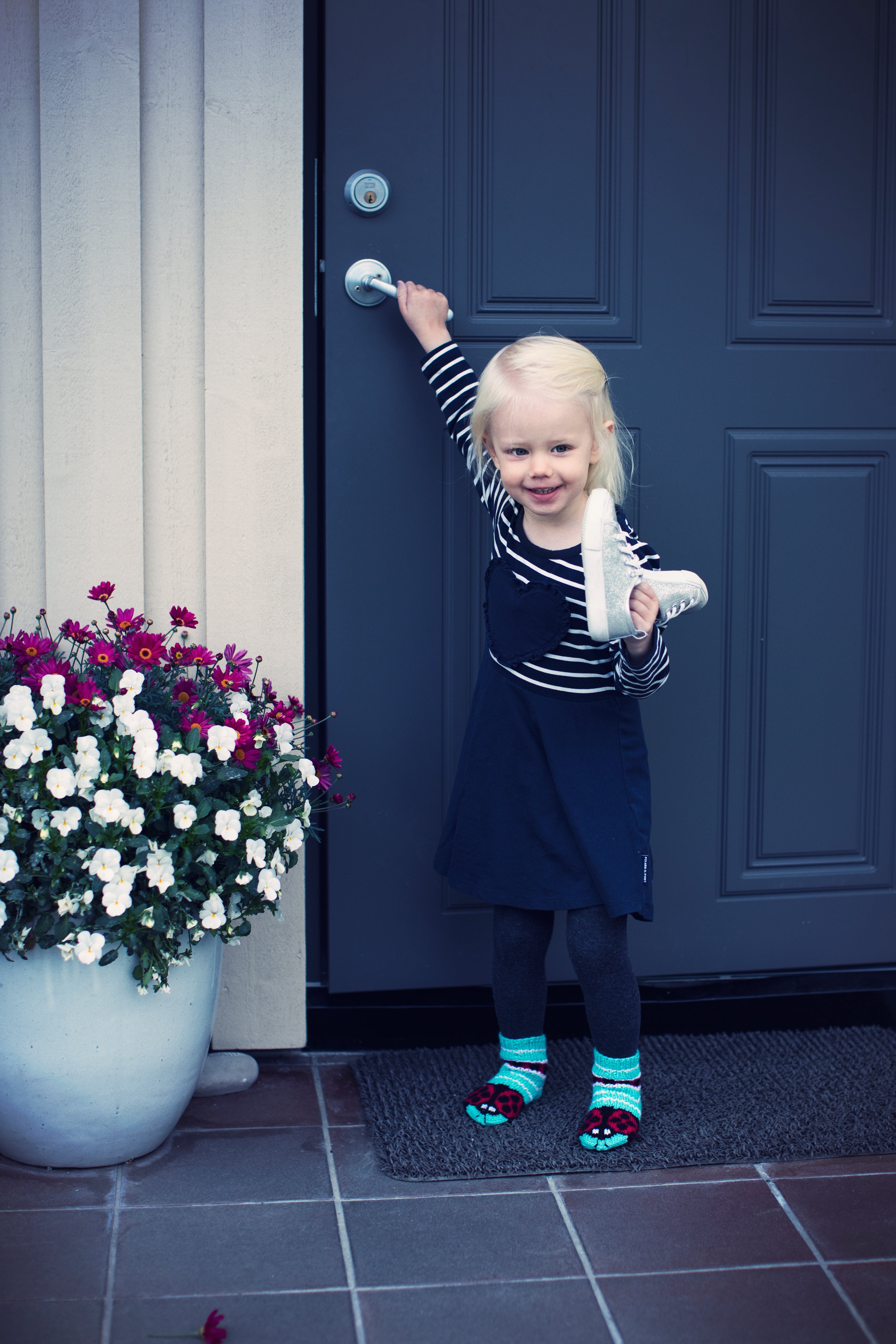 Lapsi sinisen oven edessä villasukat jalassaan